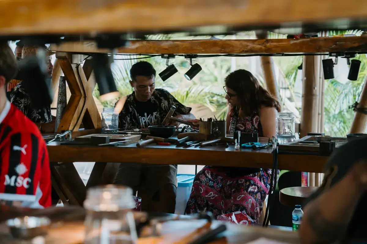 Instructor guiding a guest at the jewelry making bench in our Canggu studio